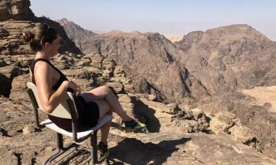 Een vrouw die op een stoel zit te genieten van het uitzicht van de backdoorhike Petra in Jordanië