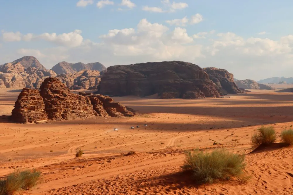 Een auto rijdt door de Wadi Rum woestijn