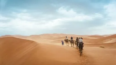 Kamelen met mensen erop die rijden door de Sahara woestijn in Marokko