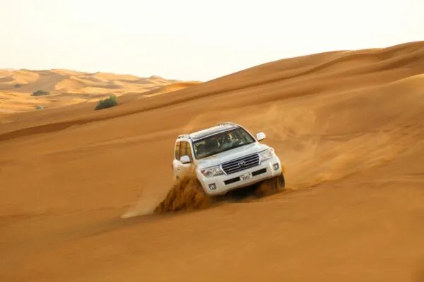 Jeep rijdend op de duinen in de woestijn Oman